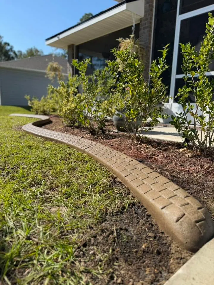 Green lawn edged with concrete curbing and a planted bed