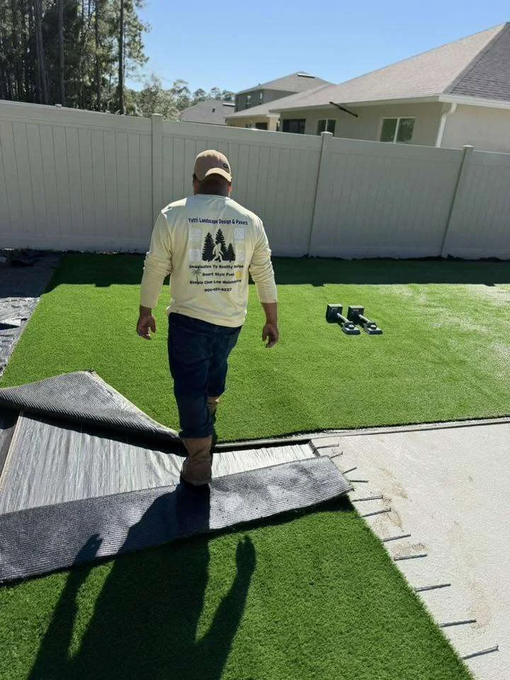 Yetti Landscaping crew member in branded shirt installing artificial turf