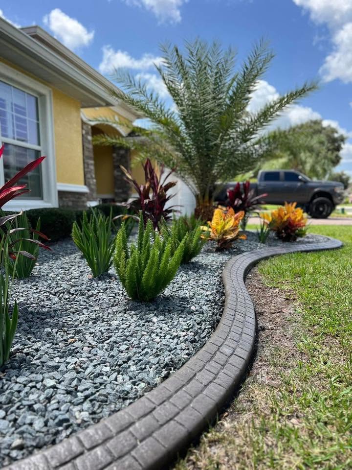 Dark stamped concrete curbing sweeping around a tropical planting bed